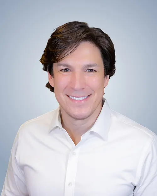 Bret Carmichael, founder of LEAP WORKS, smiling in a white collared shirt.
